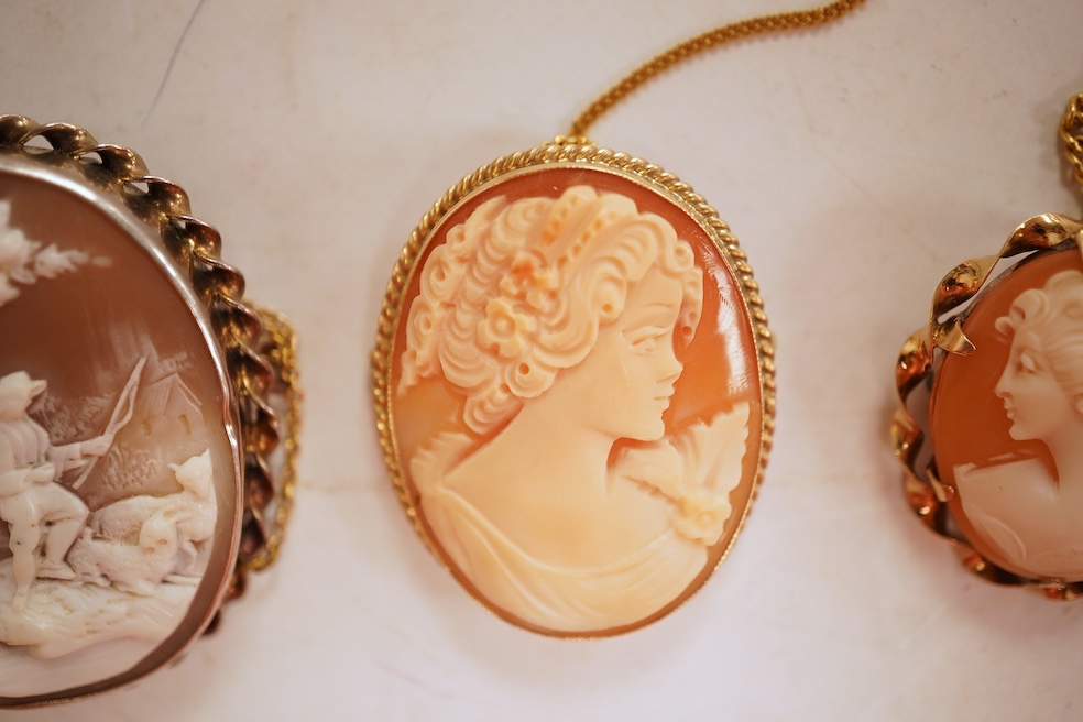 A collection of five cameo brooches, each of oval outline, set with a carved shell cameo, variously depicting three women in profile, a seated lady doing needlework, and a pastoral scene of a shepherd, longest 6.8cm, thr